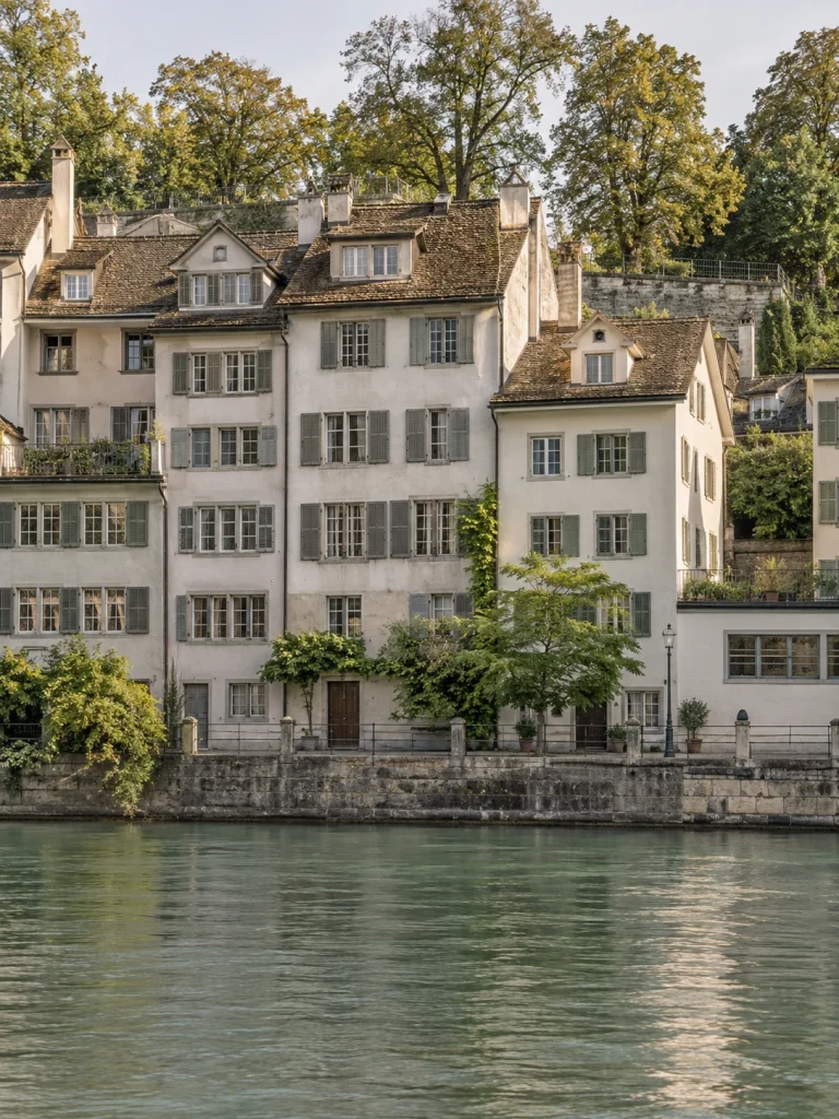 Pale riverside houses with shutters and tiled roofs beside the Limmat