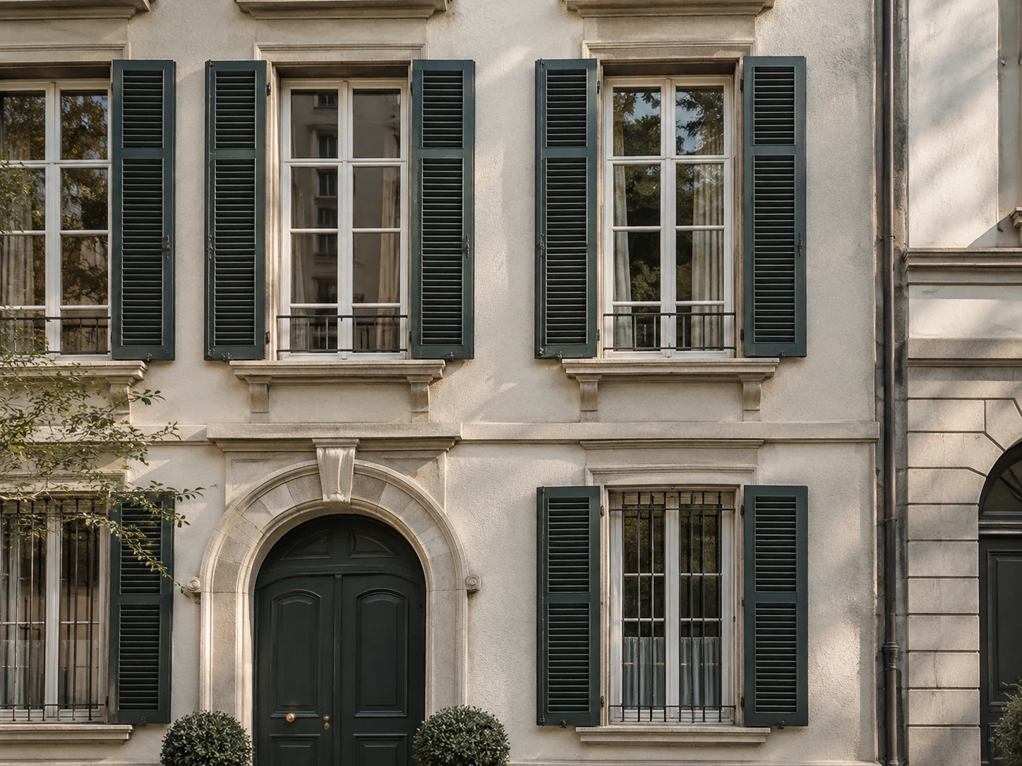 Ivory townhouse facade with charcoal-green shutters and sandstone window surrounds